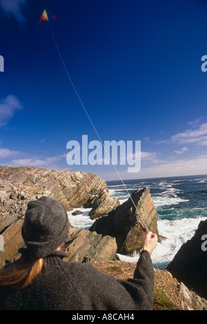 Donna aquilone volante sulle scogliere che si affacciano sull'oceano Canada Foto Stock