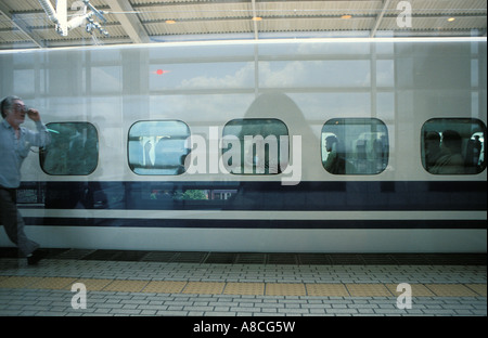 Uomo giapponese fretta lungo la piattaforma per catturare gli Shinkansen highspeed Bullet Train a Kyoto stazione ferroviaria, Giappone, Asia Foto Stock