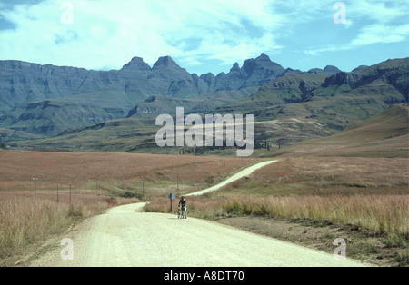 Strada che conduce alla Cattedrale di picco montagne Drakensberg Sud Africa un uomo sta spingendo un bicyle Foto Stock