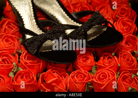 Nero ad alta scarpe tacco su un letto di rose rosse Foto Stock