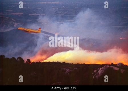 Vista aerea di un Douglas DC-6B idrica antincendio aereo bombardiere caduta ritardante del fuoco nel corso di un incendio al tramonto, fiamme, Provenza, Francia, Europa Foto Stock