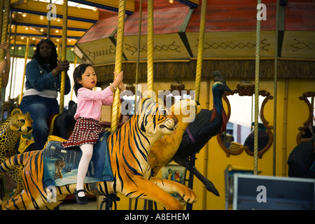 CHICAGO Illinois giovane ragazza asiatica ride tiger su specie in via di estinzione giostra su Merry Go Round al Lincoln Park Zoo Foto Stock