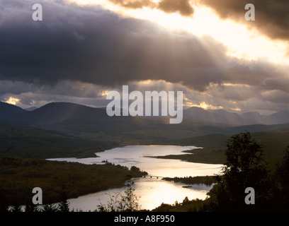 Crepuscolare raggi di sole raggi di sole attraverso Nero pioggia nuvole sopra Loch Garry su un giorno di tempesta. Glen Garry Highland Scozia UK Foto Stock