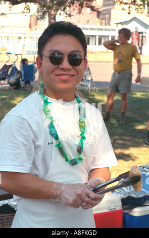 Felice uomo asiatico età 21 per la cottura di uova a rulli di supporto di concessione. Fiera di stato St Paul Minnesota USA Foto Stock