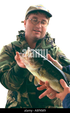 Orgoglioso pescatore età 30 visualizzazione grande bocca Bass catturato sul Lago di Roy. Nisswa Minnesota USA Foto Stock