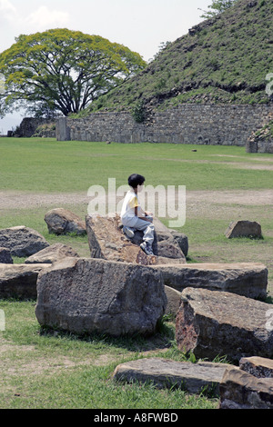 Bambino seduto su una pila di rocce a Monte Alban sito archeologico vicino a Oaxaca Messico Foto Stock