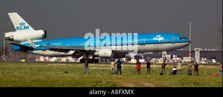 Appassionati di aerei di guardare un KLM Boeing MD11 terra sotto un cielo tempestoso all aeroporto Schipol di Amsterdam Foto Stock