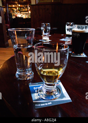 Un bicchiere di whiskey / whisky con altre bevande alcoliche su una tabella pub in Irlanda Foto Stock