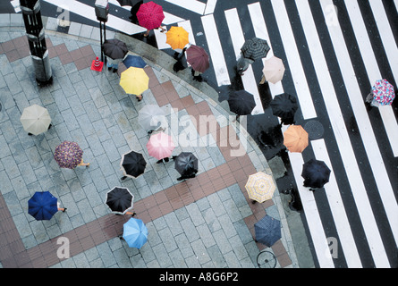 Persone con ombrelloni su attraversamento pedonale in intersezione, Ginza, Tokyo, Giappone Foto Stock