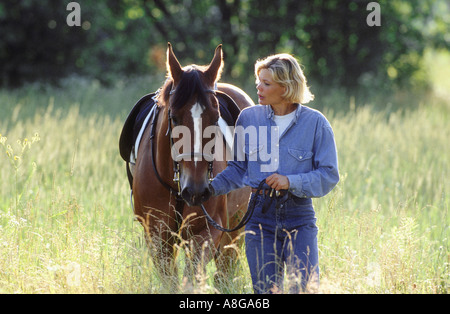 Donna passeggiate a cavallo nel campo Foto Stock