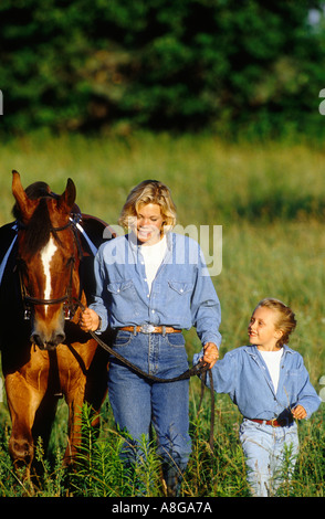 Madre e figlia camminare in campo con cavallo Foto Stock