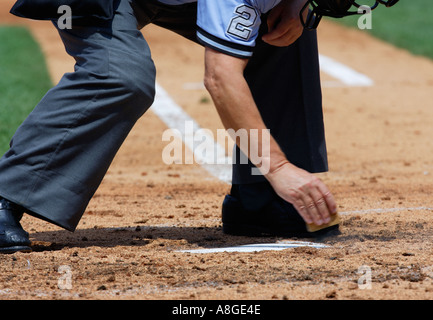 Arbitro brushing off home plate Foto Stock