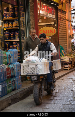 Proprietario del negozio dà istruzioni al ragazzo delle consegne su scooter al Mercato della Vucciria Palermo Sicilia Italia Foto Stock