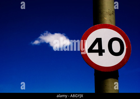 Cartello stradale 40 miglia per ora il limite massimo di velocità contro il cielo blu scuro con un singolo soffice nuvola bianca in background Foto Stock
