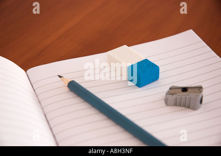 Il quaderno temperamatite e gomma sul banco di scuola Foto Stock