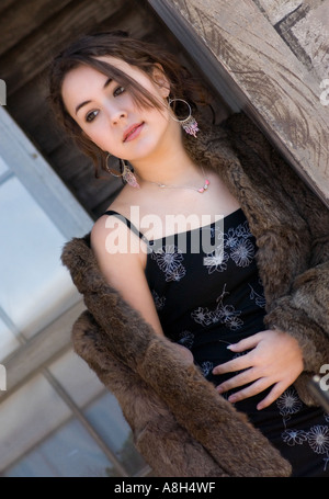 Adolescente caucasica con un elegante cappotto di pelliccia sopra un abito colorato, che sfoggia un tocco di tendenza negli Stati Uniti Foto Stock