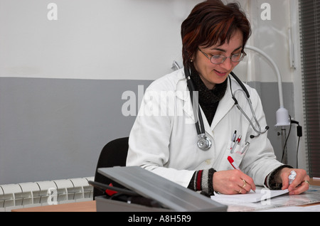 Medico donna seduta alla scrivania, la scrittura di una prescrizione Foto Stock