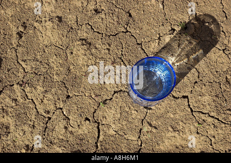 Bicchiere di acqua sul crack terra vista in elevazione Foto Stock