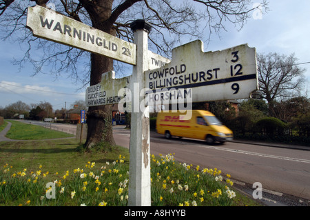 Un giallo corriere DHL van velocità passato una vecchia strada di legno segno sulla A272 a Bolney Sussex sul modo di Horsham Foto Stock