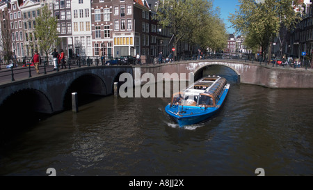 Un giro turistico in battello passa sotto un ponte sul canale di Amsterdam Foto Stock