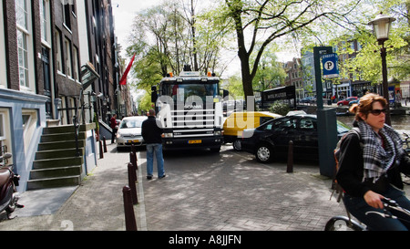 Un grande camion cercando di passare le macchine parcheggiate in Amsterdam Foto Stock