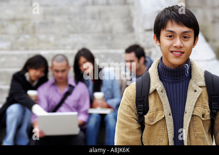 Ritratto di un giovane uomo sorridente con i suoi amici seduti in background Foto Stock