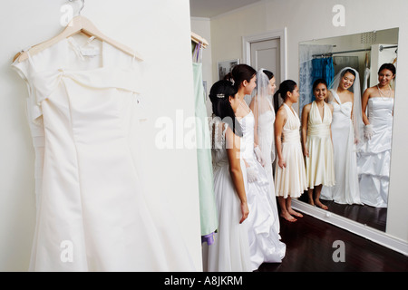 Tre giovani donne che indossano abiti da sposa e guardare a se stessi in uno specchio Foto Stock