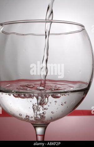 L'acqua versata in un bicchiere Foto Stock