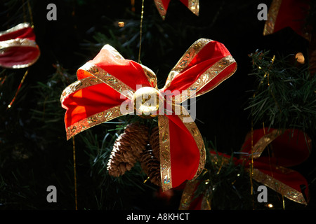 Albero di natale con decorazioni in oro e nastro rosso di prua coni fir e tinsel Foto Stock