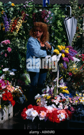 Donna vendita di fiori artificiali da lei in stallo il Mercato Centrale di Riga, Lettonia. Foto Stock