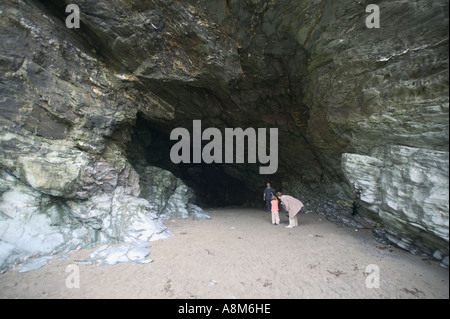 La gente in bocca della grotta di Merlin nella roccia al di sotto del castello di Tintagel Tintagel Cornovaglia Gran Bretagna Foto Stock