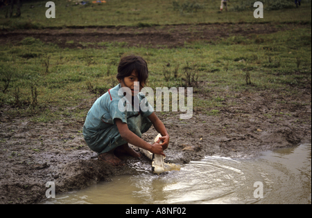 Messico Chiapas Santa Esmeralda Refugee Camp un giovane rifugiato guatemalteco ragazza di lavaggio di un cassone di bianco in una pozza di fango Foto Stock