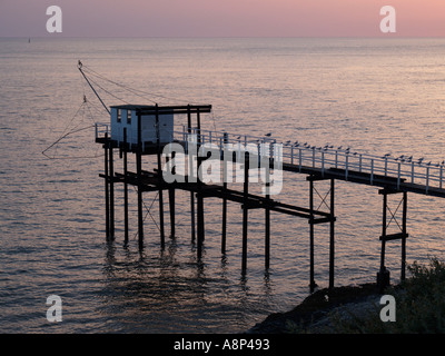 Cabina di pesca in riva al mare in Saint Palais Francia shot al tramonto con i gabbiani in appoggio sul corrimano Foto Stock