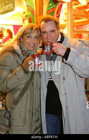 Coppia felice bevendo un vin brulé sul mercato di natale Foto Stock