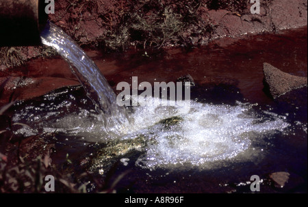 Versare l'acqua nella diga dal tubo Foto Stock