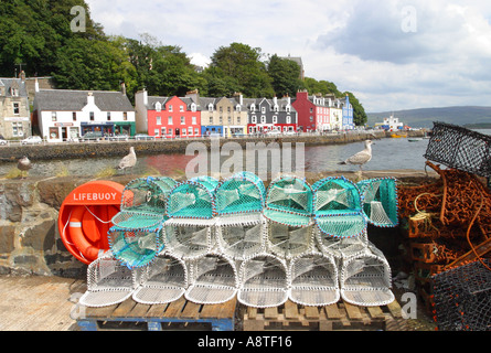 Tobermory sull'Isle of Mull Scotland harbour scena con reti da pesca sul lato del porto con colorati negozi dietro Foto Stock