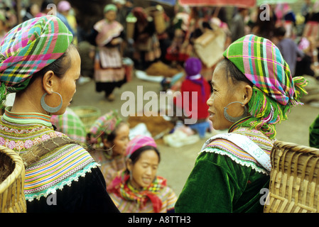 Due fiori donne Hmong in colorate abbigliamento tradizionale di parlare al mercato di domenica, Bac Ha, NW Viet Nam Foto Stock