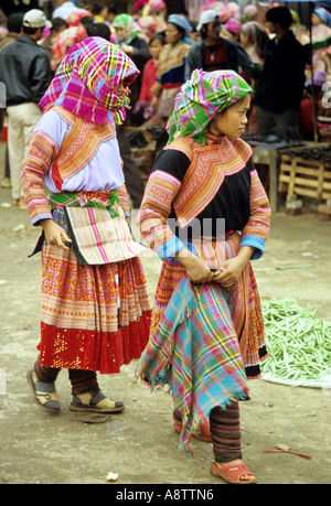 Due giovani tradizionalmente condita fiore donne Hmong a piedi attraverso il mercato della domenica, Bac Ha, NW Viet Nam Foto Stock