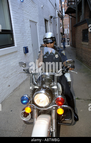 Motociclo ispanica poliziotto sulla sua Harley Davidson Moto i colloqui per la radio in uno stretto vicolo. Foto Stock