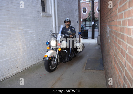 Motociclo ispanica poliziotto sulla sua Harley Davidson in uno stretto vicolo. Foto Stock