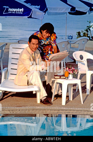 Singapore. Imprenditore cinese e la giovane donna all'aperto sulla terrazza della piscina degli hotel Novotel. Foto Stock