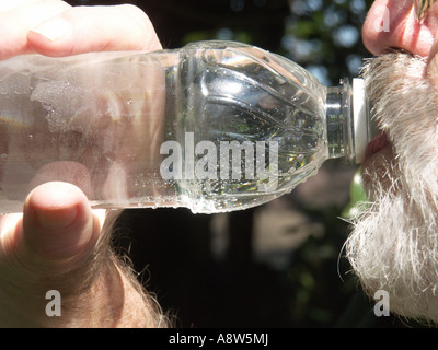 Uomo maturo di bere acqua in bottiglia. Foto Stock