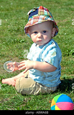 Otto mesi di vecchio bimbo seduto in un giardino. Foto Stock