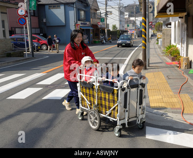I bambini piccoli di un carrello sono spinti al di là della strada a Kamakura, Giappone Foto Stock