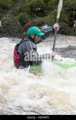 Un canoeist battaglie il torrente acque del fiume Dart in Devon England Foto Stock