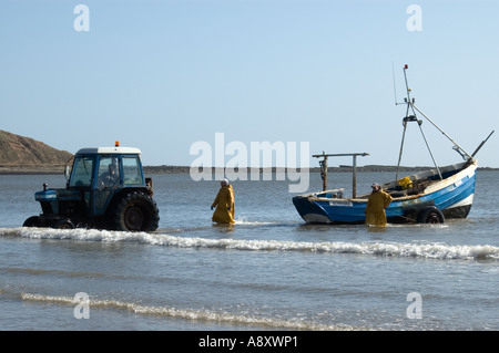 Coble pescatori portando le loro catture dopo un viaggio di pesca in mare al coble sbarco Filey Foto Stock