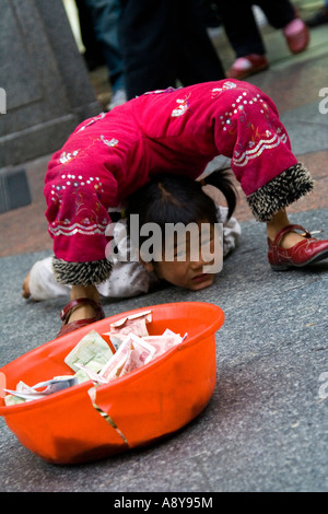 Ragazza cinese Street Performer e mendicante Shang Xia Jiu Square una trafficata strada pedonale per lo shopping mall a Guangzhou in Cina Foto Stock