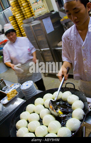 Gli spruzzi di olio sulle ciambelle di frittura in un ristorante a Guangzhou in Cina Foto Stock