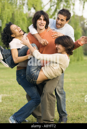 Giovani saltando su amico scherzosamente Foto Stock