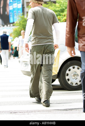 Giovane uomo attraversando via Foto Stock